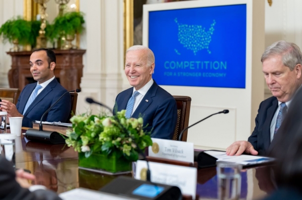 President Biden sits in front of a screen that reads 